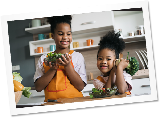 two smiling girls making a salad